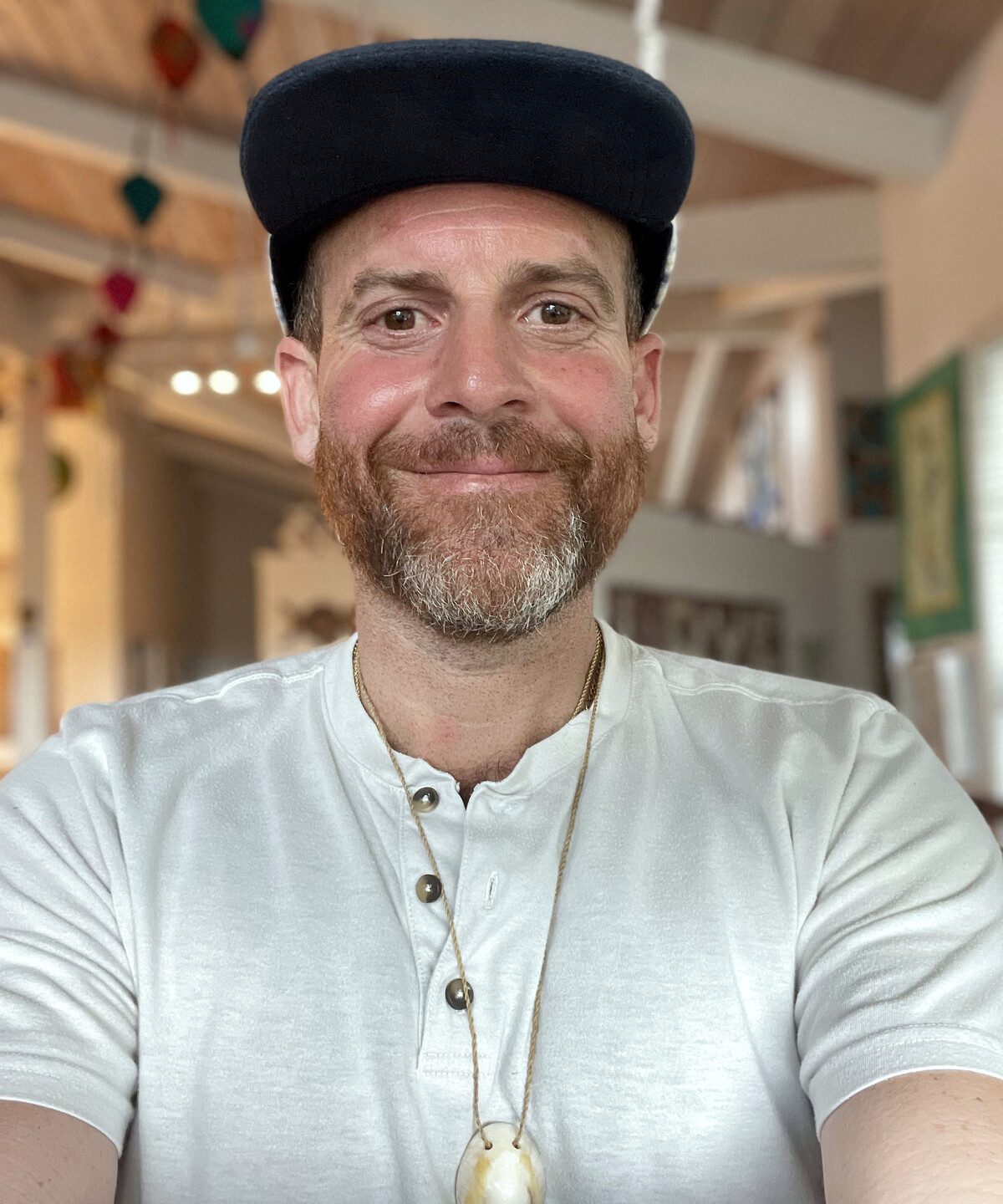 Aaron, founder and maker of Holo Holo Bolo, wearing an ʻopihi shell lei he made himself — a polished, wet-drilled ʻopihi on hau (hibiscus-bark) cordage he twisted by hand at a Volcano Art Center cordage class. Not a bolo.